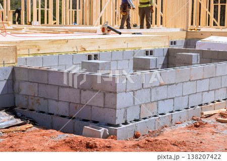Construction workers build block wall foundation for new house in residential area 138207422