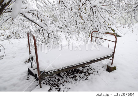 Snow fell in the garden. The old bed under a tree in the garden. Winter has come 138207604