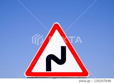 Road sign dangerous turn. Warning sign. 138207646
