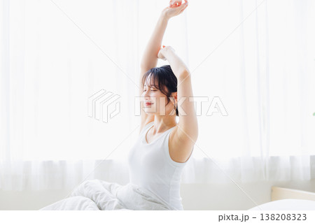 朝の寝室で伸びをする若い女性 138208323