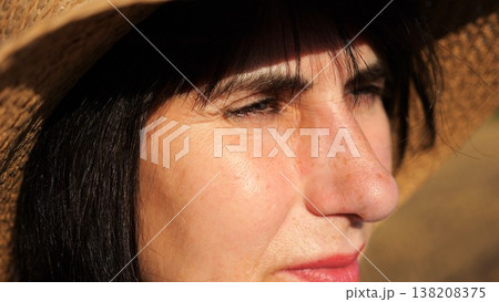 Female farmer in straw hat looking into wheat field and examining plantation at sunset. Close up face of adult beautiful woman illuminating by bright rays of sun. Concept of agriculture business Female farmer in straw hat looking into wheat field and examining plantation at sunset. Close up face of adult beautiful woman illuminating by bright rays of sun. Concept of agriculture business 138208375