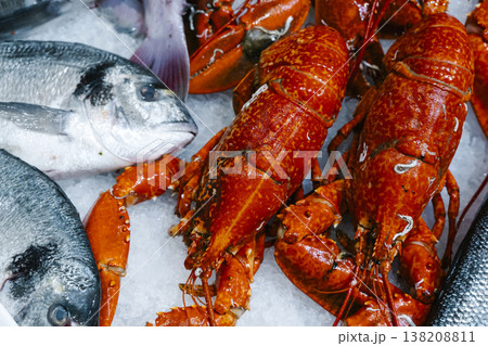 Seafood selection with red lobsters and fresh fish on ice. Top view of a luxury market display featuring gourmet crustaceans and silver sea bream at a traditional fish stall 138208811