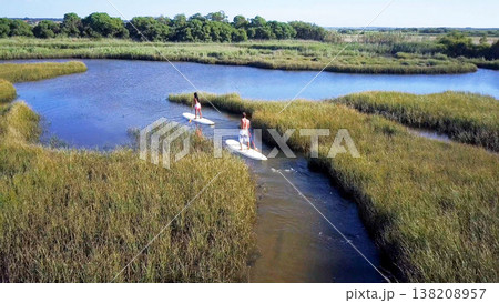 Man and woman stand up paddleboarding Man and woman stand up paddleboarding 138208957