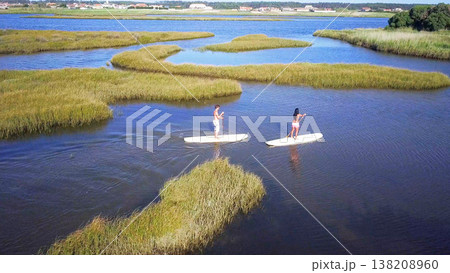Man and woman stand up paddleboarding Man and woman stand up paddleboarding 138208960