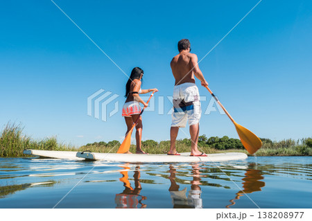 Man and woman stand up paddleboarding Man and woman stand up paddleboarding 138208977