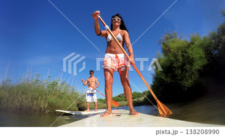 Woman stand up paddleboarding Woman stand up paddleboarding 138208990