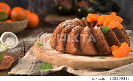 Glazed Orange Bundt Cake Topped with Fresh Mandarin Segments and Powdered Sugar on a Rustic Wooden Table Glazed Orange Bundt Cake Topped with Fresh Mandarin Segments and Powdered Sugar on a Rustic Wooden Table 138209312