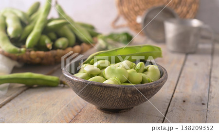 Fresh shelled broad beans in a rustic ceramic bowl on a wooden table 138209352
