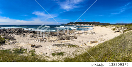 Panoramic view of Praia do Forte do Cao beach in Portugal with rocky shoreline and blue sky 138209373