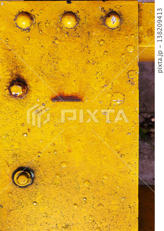 Yellow painted metal plate with rivets, rust spots, and scratches. Industrial grunge texture background with weathered surface and corrosion. Yellow painted metal plate with rivets, rust spots, and scratches. Industrial grunge texture background with weathered surface and corrosion. 138209413