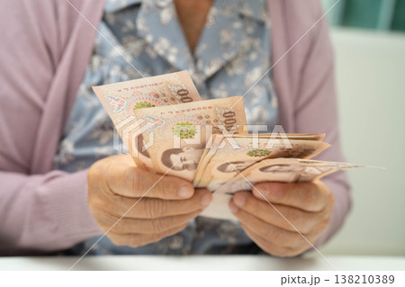 Retired elderly woman counting coins money and worry about monthly expenses and treatment fee payment. Retired elderly woman counting coins money and worry about monthly expenses and treatment fee payment. 138210389