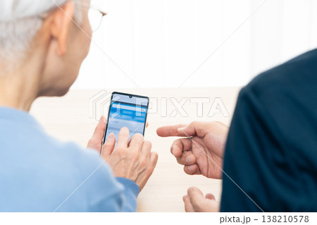 スマホアプリの使い方の説明を受けるシニア女性 スマホアプリの使い方の説明を受けるシニア女性 138210578