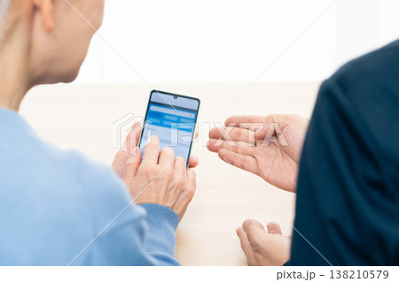 スマホアプリの使い方の説明を受けるシニア女性 138210579