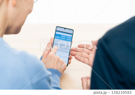 スマホアプリの使い方の説明を受けるシニア女性 スマホアプリの使い方の説明を受けるシニア女性 138210583