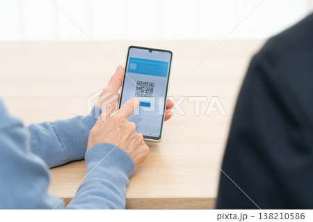 スマホアプリの使い方の説明を受けるシニア女性 138210586