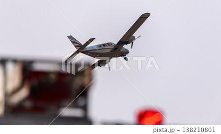 Airplane taking off with landing gear extended against a sky background, with blurred red airport equipment lights in the foreground 138210801