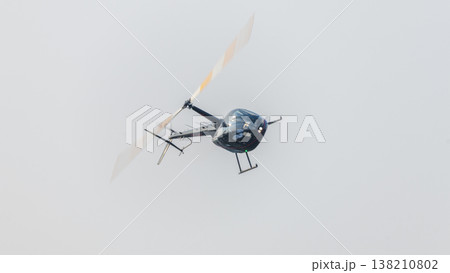 Helicopter flying with motion-blurred rotor blades against a clean sky background during an aerial demonstration at an airshow. Dynamic aviation scene with a sense of movement 138210802