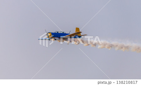 Aircraft performing an aerobatic maneuver with a smoke trail against a clear sky during an aerial aviation display Aircraft performing an aerobatic maneuver with a smoke trail against a clear sky during an aerial aviation display 138210817