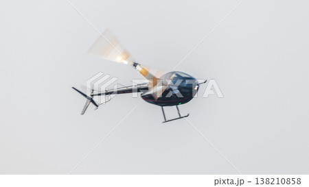 Helicopter flying with motion-blurred rotor blades against a clean sky background during an aerial demonstration at an airshow. Dynamic aviation scene with a sense of movement 138210858