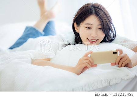 ベッドでスマホを見る女性 ベッドでスマホを見る女性 138213453