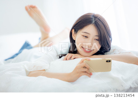 ベッドでスマホを見る女性 ベッドでスマホを見る女性 138213454