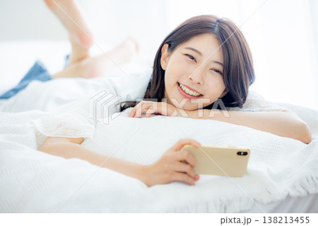 ベッドでスマホを見る女性 ベッドでスマホを見る女性 138213455