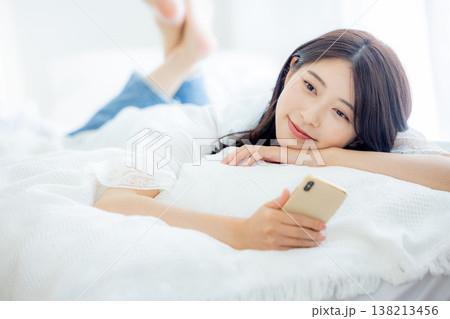 ベッドでスマホを見る女性 138213456