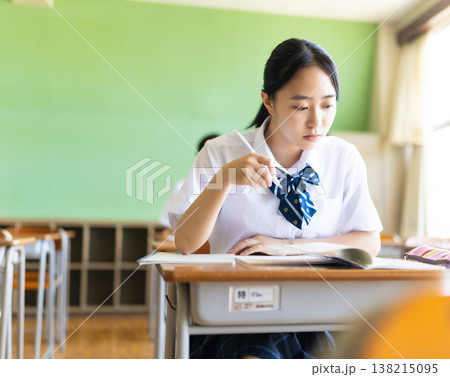 教室で真剣に筆記する女子生徒 138215095
