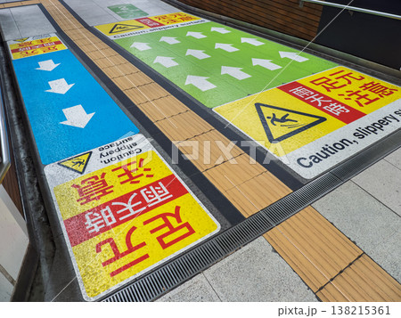 色分けされた矢印と注意表示が並ぶ駅構内の路面標示(足元注意) 色分けされた矢印と注意表示が並ぶ駅構内の路面標示(足元注意) 138215361