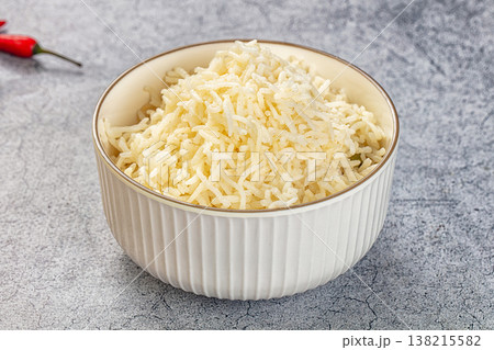 Steamed long-grain white rice in a bowl on a gray textured background. 138215582