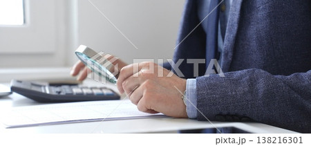 Financial analyst reviewing accounting reports, calculating data with calculator and magnifying glass on corporate workspace. Audit and taxes in business Financial analyst reviewing accounting reports, calculating data with calculator and magnifying glass on corporate workspace. Audit and taxes in business 138216301