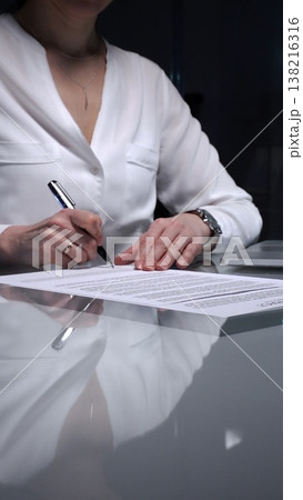 Businesswoman signing a contract late in the office, closing a deal, or completing legal paperwork at deep night. Audit and overworking concepts 138216316