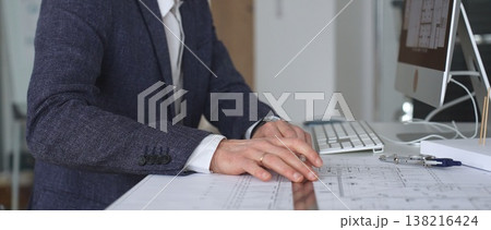 Architect hand drawing on building blueprints, architectural model and computer on desk,. Modern architecture and construction concept 138216424