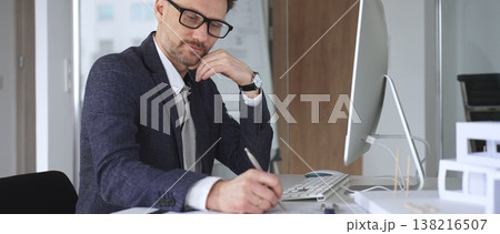 Architect man thinking while working on blueprints and computer, planning new building design in office. Business and architecture concept 138216507
