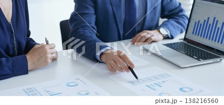 Business professionals reviewing financial data, pointing at laptop charts and shared documents during collaborative strategy session. Business people and finance concept 138216560