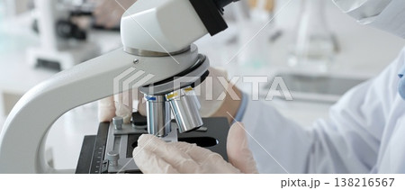 White gloved hands of scientist professional adjusting a microscope in a bright laboratory, emphasizing precision and focus in scientific research. Medicine, healthcare and science concept White gloved hands of scientist professional adjusting a microscope in a bright laboratory, emphasizing precision and focus in scientific research. Medicine, healthcare and science concept 138216567