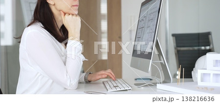 Adult woman architect analyzing construction blueprint on computer screen in modern design office, planning and thinking about new building project. Business and architecture concept Adult woman architect analyzing construction blueprint on computer screen in modern design office, planning and thinking about new building project. Business and architecture concept 138216636