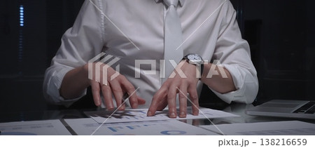 Business professional analyzing financial data with charts and reports on desk, working late in dark office. Audit and overworking concepts 138216659