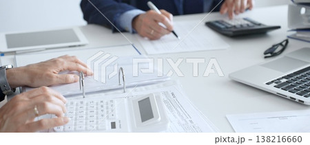 Close up of female accountant hands using calculator while collaborating with male colleague in office, calculating taxes and analyzing financial data. Audit and taxes in business 138216660