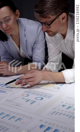 Business colleagues collaborating on financial reports, analyzing market data and corporate strategy by reviewing charts and graphs on a table in an office meeting Business colleagues collaborating on financial reports, analyzing market data and corporate strategy by reviewing charts and graphs on a table in an office meeting 138216892