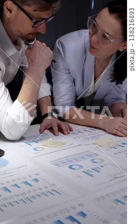 Business colleagues collaborating on financial reports, analyzing market data and corporate strategy by reviewing charts and graphs on a table in an office meeting Business colleagues collaborating on financial reports, analyzing market data and corporate strategy by reviewing charts and graphs on a table in an office meeting 138216893