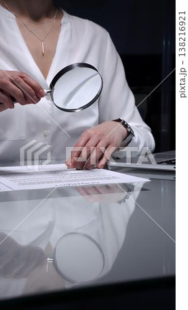 Woman analyzing contract text with magnifying glass, scrutinizing fine print for legal details and agreement review. Audit, business and overworking concepts 138216921