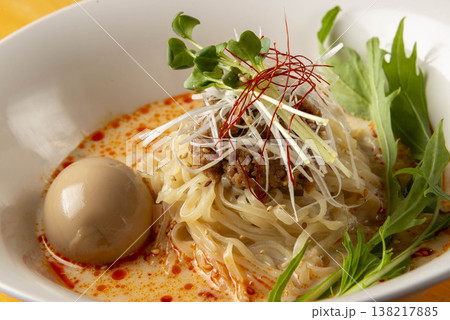 濃厚で美味しい油そば。辛いスープ、細い麺、温泉卵、野菜がトッピングされている 138217885