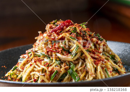 赤唐辛子とネギをトッピングした、辛味が効いた麺料理。アジア風の立体的な盛り付けの焼きそば 赤唐辛子とネギをトッピングした、辛味が効いた麺料理。アジア風の立体的な盛り付けの焼きそば 138218168