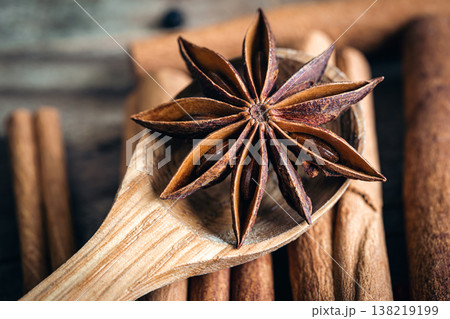 Star anise on a wooden spoon on a blurred background of cinnamon sticks. Star anise on a wooden spoon on a blurred background of cinnamon sticks. 138219199