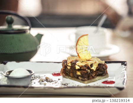Stylish green kettle with tea and sweet dessert. Caramelized Apple Pie with Lemon and Cold Ice Cream 138219314