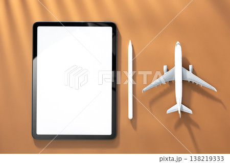 Tablet and airplane miniature on brown background, top view, copy space. Tablet and airplane miniature on brown background, top view, copy space. 138219333