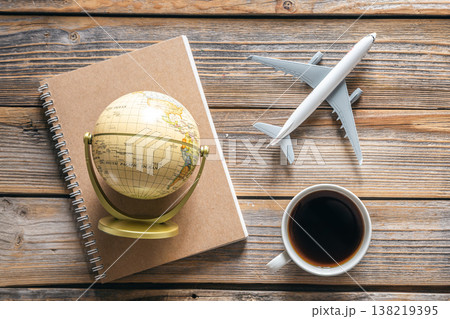 Travel composition with notepad, globe, airplane model and coffee cup, top view. Travel composition with notepad, globe, airplane model and coffee cup, top view. 138219395