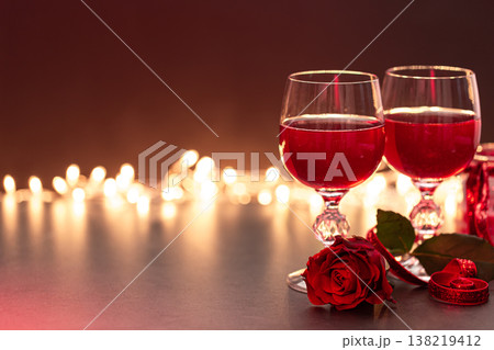 Two glasses of wine and a red rose on a blurred background with bokeh. Two glasses of wine and a red rose on a blurred background with bokeh. 138219412