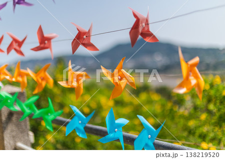 Colorful Pinwheels Hanging On String With Blurred Tropical Landscape Background Colorful Pinwheels Hanging On String With Blurred Tropical Landscape Background 138219520